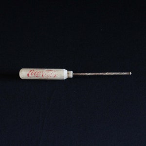 Op de afbeelding: Een houten schroevendraaier met een rood "Coca-Cola" logo op de handgreep.