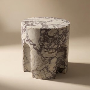 May include: A cylindrical side table crafted from white marble with prominent dark purple veining. The piece features a smooth, flat circular top and a base with three distinct, recessed vertical arch cutouts that create a scalloped profile.