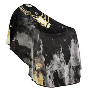 May include: Black barber cape with a gold chain and a gold pendant featuring a microphone design. The cape has a white and grey flame design.