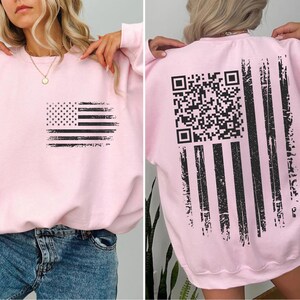 The image is a collage of two photos. In the first photo, a woman is wearing a pink sweatshirt with a black American flag design on the front. In the second photo, the woman is wearing the same pink sweatshirt with a black QR code on the back.