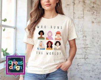 May include: White t-shirt with the text "Who runs the world?" and illustrations of diverse women's faces.