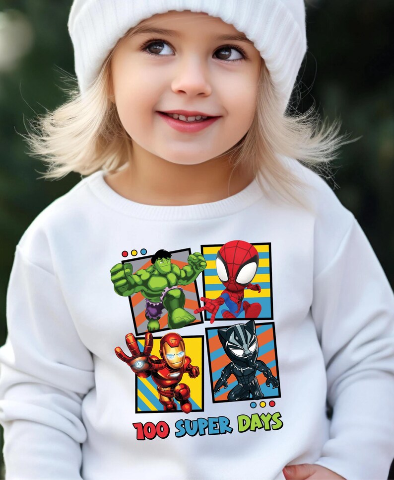 A young girl wearing a white beanie and a white sweater with a graphic of four cartoon characters: the Hulk, Spider-Man, Iron Man, and Black Widow.