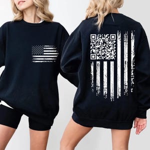 two black sweatshirts with white designs on the back. The design on the back includes an American flag and a QR code.