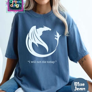 a woman wearing a blue t - shirt with a white dragon on it