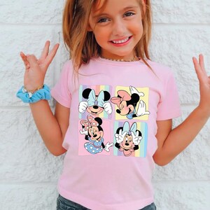 a little girl wearing a pink shirt with mickey mouse on it