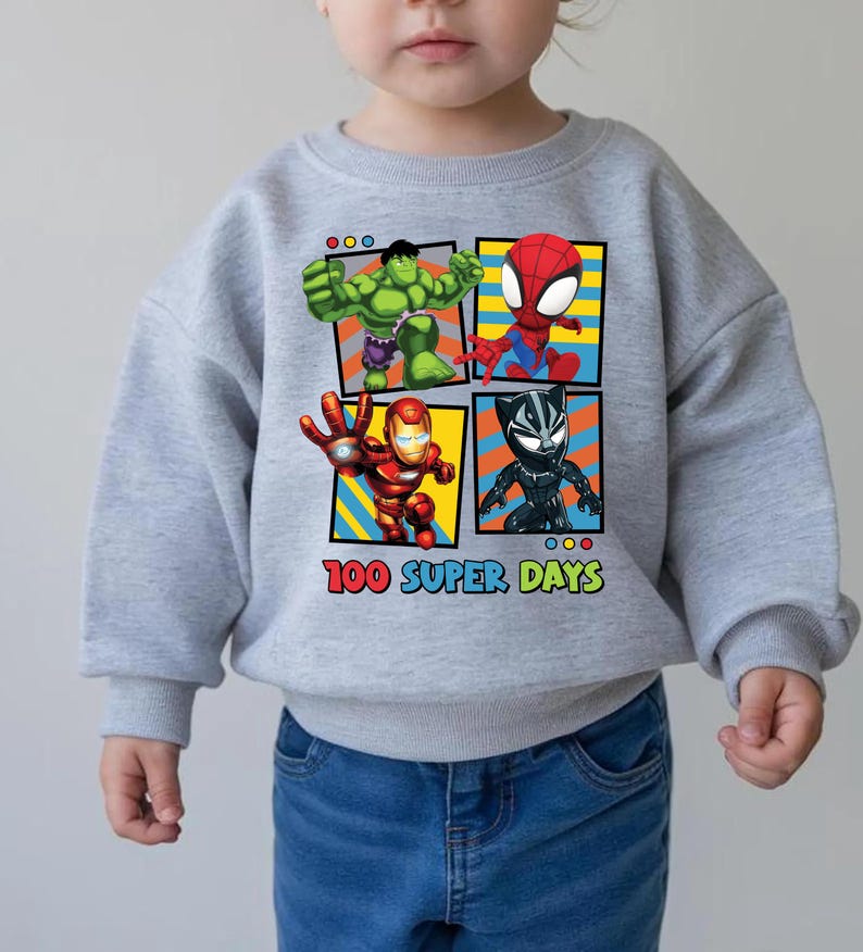 A child wearing a gray sweatshirt with a graphic of four superhero characters: Hulk, Spider-Man, Iron Man, and Black Widow, along with the text "100 SUPER DAYS".