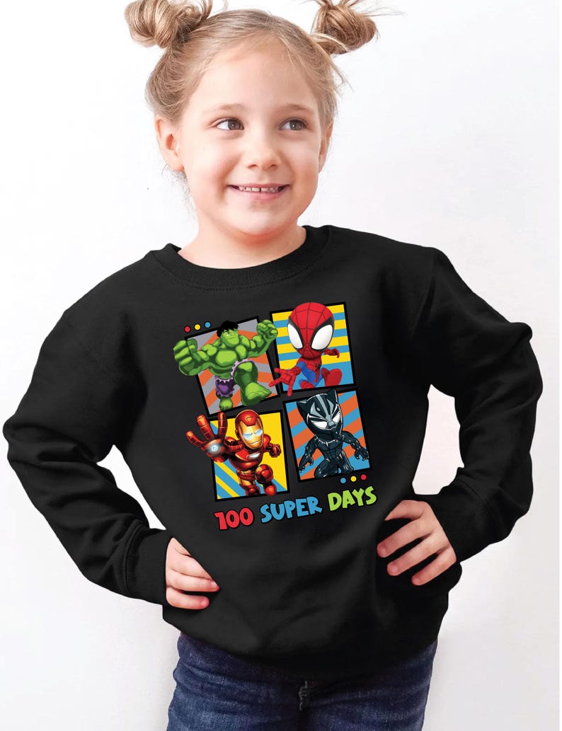 A young girl wearing a black sweatshirt with a graphic of four superhero characters: Hulk, Spider-Man, Black Widow, and Iron Man.