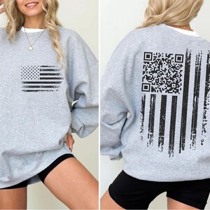The image is a collage of two photos showing the back and front of a gray sweatshirt with a graphic design featuring an American flag and a QR code.