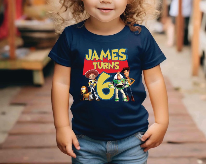 a little girl wearing a blue shirt with the name james turns 6 on it