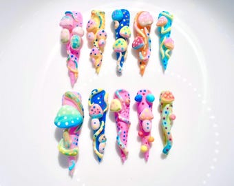 May include: A collection of ten long, sculpted fingernails with a whimsical mushroom theme. Each nail features a different design, with vibrant colors like pink, blue, yellow, and orange. The mushroom details are 3D, adding texture and visual interest.