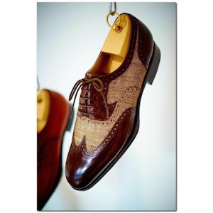 Peut inclure: Une chaussure oxford en cuir marron avec un panneau en tissu tissé beige et des surpiqûres décoratives. La chaussure a une fermeture à lacets et une pointe pointue.