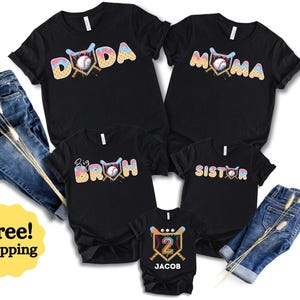 May include: Five black t-shirts featuring a baseball-themed graphic with ice cream cone textures and colors. The shirts display the text DODA, MOMA, BIG BROH, SISTER, and the number 2 with the name JACOB. Two pairs of blue denim jeans are included.