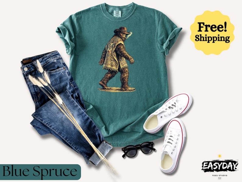May include: A teal t-shirt with a graphic of a Bigfoot-like creature wearing a hat and poncho, paired with blue jeans, white sneakers, and black sunglasses. The words "Blue Spruce" are at the bottom.