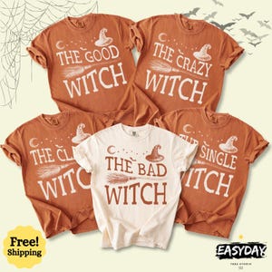 May include: Four short-sleeved crew neck t-shirts featuring witch-themed graphics. Three shirts are burnt orange with white text reading The Good Witch, The Crazy Witch, and The Single Witch. One centre shirt is cream with brown text reading The Bad Witch.