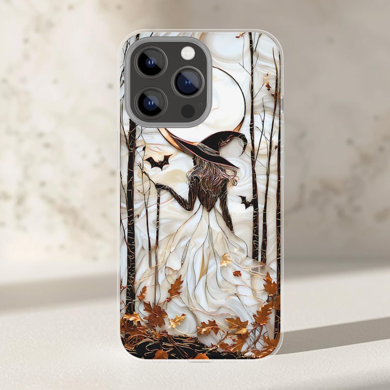 May include: A phone case with a witch design, wearing a white dress and black hat, set in a forest with a full moon. The artwork includes bats, autumn leaves, and bare trees, perfect for Halloween.