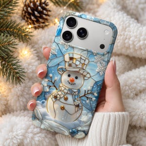 Puede incluir: Una funda para smartphone con un diseño estilo vidriera de un muñeco de nieve con sombrero de copa. El fondo es un patrón de mosaico azul claro con copos de nieve blancos. El muñeco de nieve tiene una nariz de zanahoria naranja.