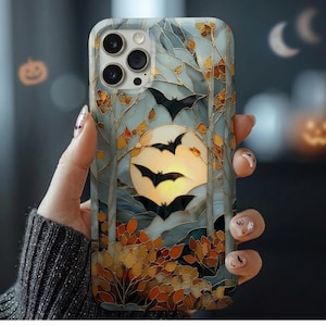 May include: A smartphone case featuring a stained-glass style design with a large yellow full moon, black silhouettes of flying bats, and autumn-colored foliage in shades of orange, brown, and gold against a pale blue and grey background.