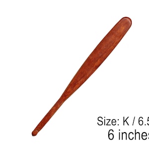 May include: A wooden, reddish-brown tool, approximately 6 inches long, with a flat, rounded end and a slender handle. The tool is labeled "Size: K / 6.5mm". The design suggests it is a specialized craft or hobby tool.