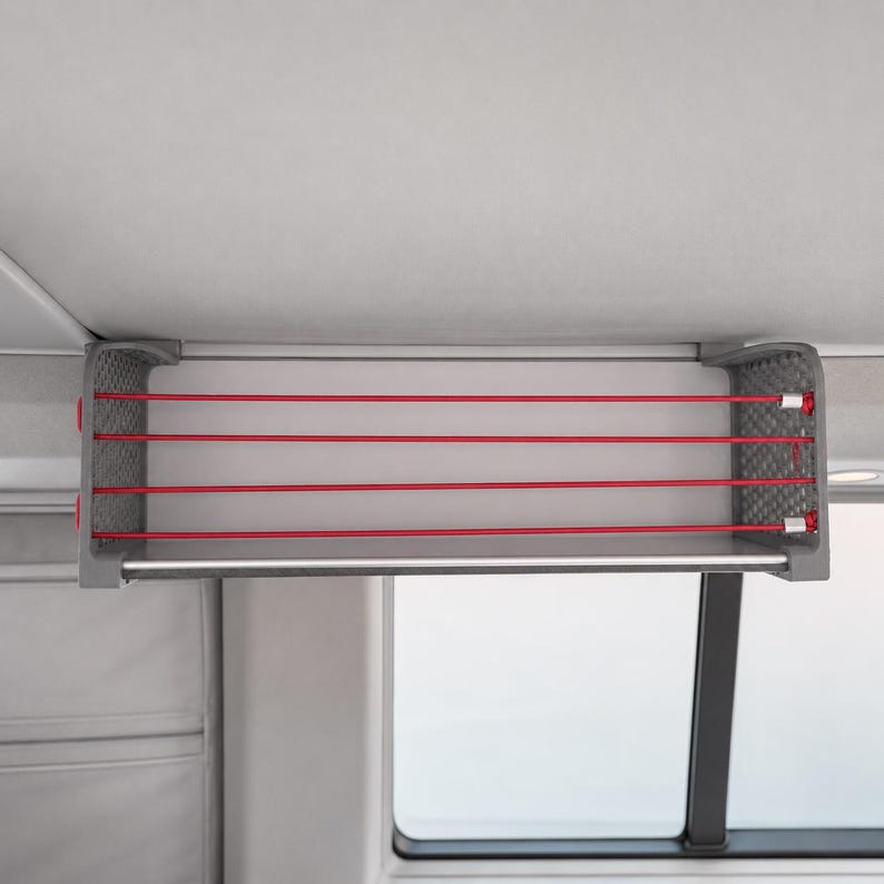 VW California Deckenregal für T5, T5.1, T6 und T6.1 im Camper-Innenraum. Dachablage mit grauen Seitenteilen, roten Gummibändern und Aluminiumstange, montiert an der seitlichen Dachschiene für zusätzlichen Stauraum.