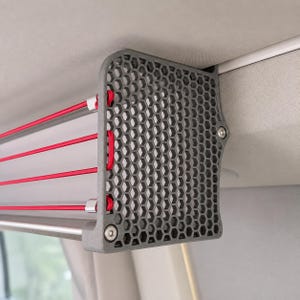 Seitenansicht: VW California Deckenregal für T5, T5.1, T6 und T6.1 im Camper-Innenraum. Dachablage mit grauen Seitenteilen, roten Gummibändern und Aluminiumstange, montiert an der seitlichen Dachschiene für zusätzlichen Stauraum.