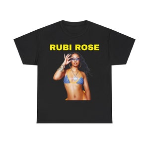 Peut inclure: T-shirt noir avec le texte "RUBI ROSE" en lettres jaunes. Une femme porte un bikini bleu et jaune et des lunettes de soleil.