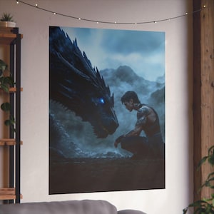 May include: A man with a tattoo on his arm sits in front of a large, black dragon with glowing blue eyes. The dragon's head is turned towards the man, and the background is a misty, blue landscape.