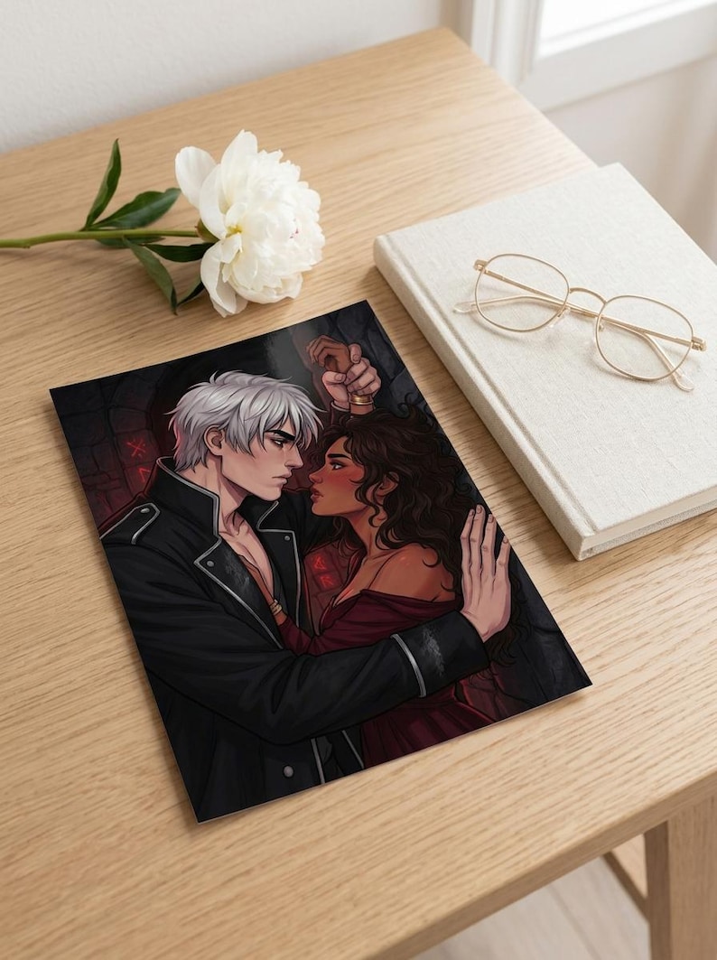 May include: An art print depicting a romantic illustration of a couple in an embrace. The man has white hair and wears a black jacket. The woman has dark hair and a red dress. A white flower, glasses, and a book are also visible.