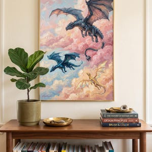 May include: A framed oil painting depicting three dragons flying through pink and blue clouds. The top dragon is dark grey, the middle is blue, and the bottom is gold. The artwork is displayed above a wooden console table filled with books.