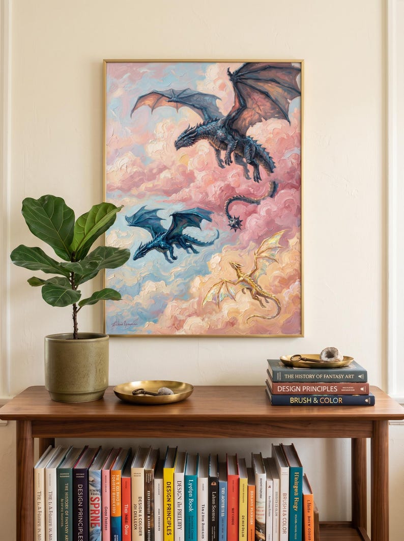 May include: A framed oil painting depicting three dragons flying through pink and blue clouds. The top dragon is dark grey, the middle is blue, and the bottom is gold. The artwork is displayed above a wooden console table filled with books.