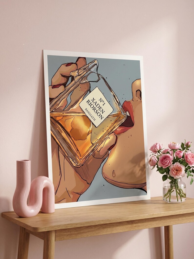 Pode incluir: Ilustra&ccedil;&atilde;o de uma pessoa bebendo de um frasco de perfume. A garrafa &eacute; quadrada com um r&oacute;tulo que diz "N&deg;1 Xaden Riorson Basgiath". A obra de arte &eacute; ambientada em um fundo azul claro, com uma mesa de madeira e flores cor-de-rosa em primeiro plano.