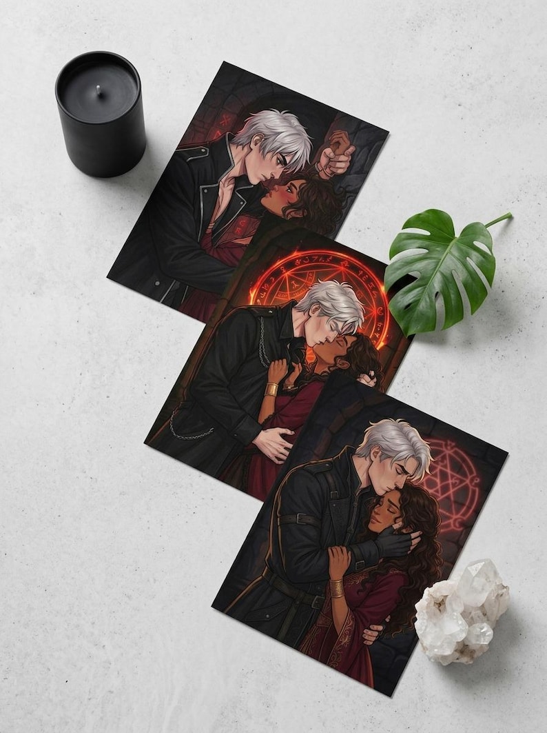 May include: Three art prints depicting romantic illustrations of a couple embracing. The man has white hair and wears a black jacket. The woman has dark hair and wears a red dress. A black candle and a monstera leaf are also present.