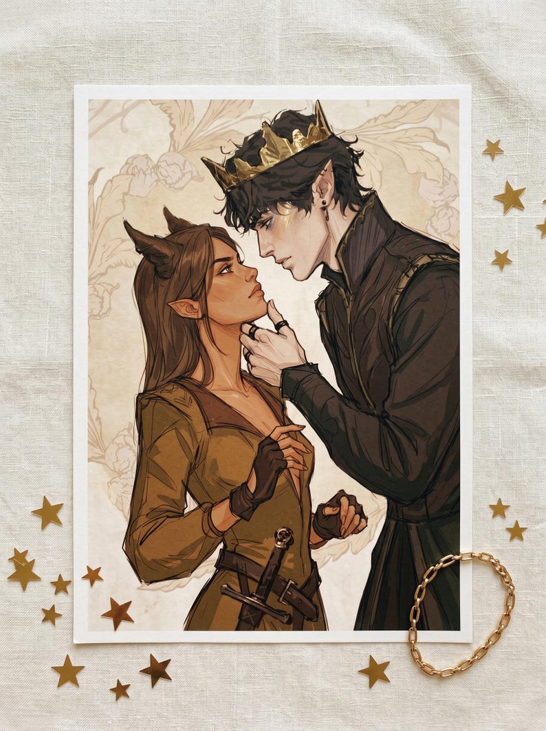 May include: An art print featuring a couple in a fantasy setting. The woman has horns and pointed ears, wearing a brown dress and gloves. The man wears a gold crown and black attire. The background has a floral pattern. Gold stars and a bracelet are scattered around.