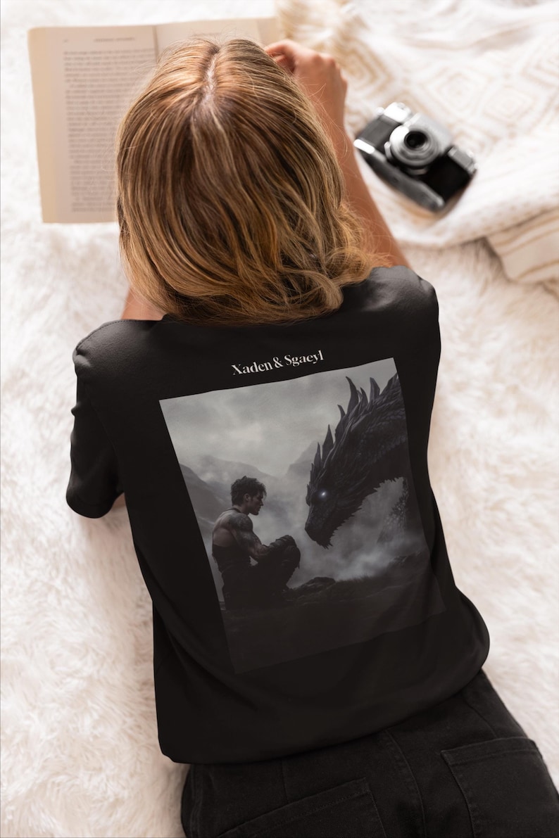 May include: Black t-shirt with a graphic print of a man and a dragon. The text "Xaden & Sgaeyl" is printed on the shirt.