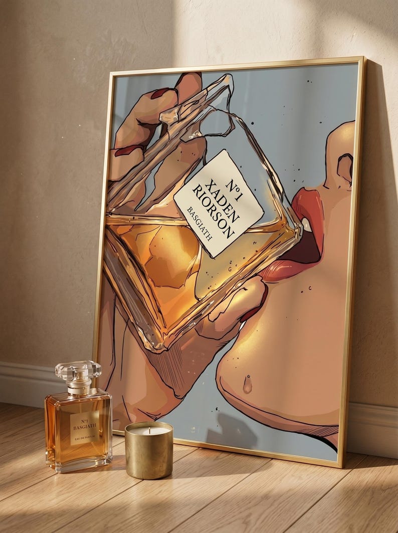 Pode incluir: Uma impress&atilde;o art&iacute;stica emoldurada com uma pessoa bebendo de um frasco de perfume. O frasco tem um r&oacute;tulo que diz "N&deg;1 Xaden Riorso Basgiath". Um frasco de perfume e uma vela dourada est&atilde;o em frente &agrave; impress&atilde;o.