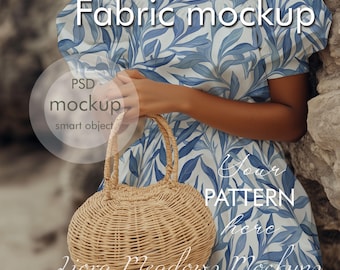 May include: A woman wearing a blue and white floral dress holds a round, woven straw bag. The dress has a leaf pattern and the text "Fabric mockup" is written across the top of the image. The text "Your pattern here" is written on the dress.