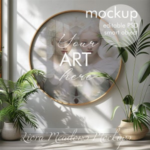 Könnte beinhalten: Ein runder Spiegel mit goldenem Rahmen, weißem Hintergrund und dem Text "Your Art Here" in der Mitte. Der Spiegel hängt an einer weißen Wand mit zwei Topfpflanzen auf jeder Seite.