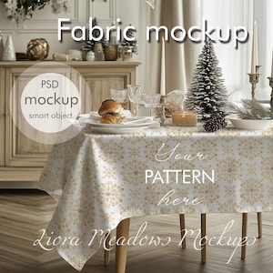Op de afbeelding: Een wit tafelkleed met een gouden sneeuwvlokkenpatroon, op een houten tafel met een kerstboom, kaarsen en een bord met gebak. De tekst "Your Pattern Here" staat op het tafelkleed. De tekst "Liora Meadows Mockups" staat op de tafel.