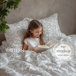 Puede incluir: Una ni&ntilde;a peque&ntilde;a sentada en la cama leyendo un libro, rodeada de ropa de cama gris y blanca con un patr&oacute;n de hojas. El texto "Your Pattern Here" es visible en la esquina inferior izquierda de la imagen. El texto "PSD Mockup Smart Object" es visible en la esquina inferior derecha de la imagen.