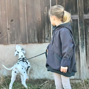 Può includere: Una bambina con una felpa con cappuccio grigia e leggings grigi passeggia con un cucciolo di dalmata al guinzaglio. La bambina guarda il cucciolo, che sta annusando il terreno.