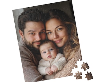May include: A family portrait puzzle featuring a couple and their baby. The couple is holding the baby, who is looking at the camera. The puzzle is made of cardboard and has a white background.