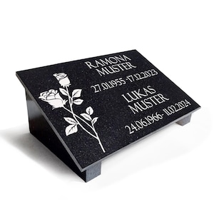 Könnte beinhalten: Schwarze Granit-Gedenktafel mit weißer Gravur und einem Rosenmotiv. Der Text lautet "RAMONA MUSTER 27.01.1955 - 17.12.2023" und "LUKAS MUSTER 24.06.1966 - 11.02.2024".