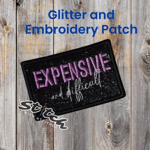 May include: A black rectangular glitter and embroidered patch with the words "EXPENSIVE and difficult" in purple and white. The patch is on a wooden background. The text "Glitter and Embroidery Patch" is above the patch.