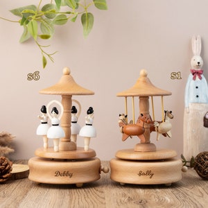 May include: Two wooden music boxes with a carousel design. One features a ballerina theme with the name "Debby" engraved on the base. The other features a horse theme with the name "Sally" engraved on the base.