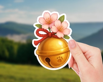 May include: A sticker featuring a golden bell with a paw print, adorned with pink cherry blossoms and a red rope. The bell has a small opening and is a decorative item.