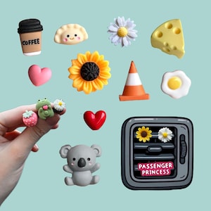 May include: A collection of small decorative charms including a coffee cup, dumpling, daisy, cheese wedge, heart, sunflower, traffic cone, fried egg, strawberry, frog, koala, and a car air vent charm with the text PASSENGER PRINCESS.
