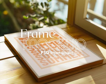 Könnte beinhalten: Ein rechteckiger Rahmen-Mockup mit den Worten "Frame mockup" und "SUMMER" in Orange und Weiß. Der Rahmen ist aus Holz und liegt auf einer Holzoberfläche. Das Bild wird von natürlichem Licht beleuchtet.
