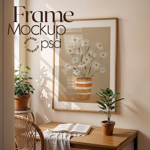 Puede incluir: Una impresión artística enmarcada que presenta un jarrón con margaritas blancas con centros amarillos. El jarrón tiene rayas naranjas y blancas. El marco es de madera. La imagen está en una habitación con plantas y un escritorio. El texto en la imagen dice "Frame Mockup / psd".