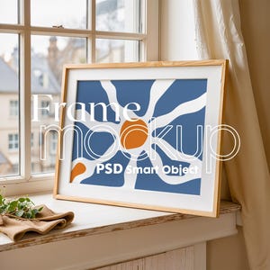Puede incluir: Una impresión de arte abstracto enmarcada con un fondo azul y formas blancas y naranjas. El marco es de madera y tiene un acabado marrón claro. El texto "PSD Smart Object" es visible en la parte inferior central de la impresión.
