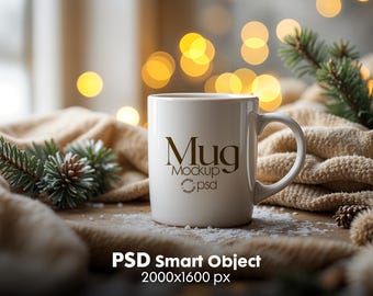May include: White ceramic mug with the text "Mug Mockup psd" in gold lettering, sitting on a beige blanket with a pine branch and a blurred background of warm yellow lights.