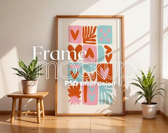 May include: A framed print with a colorful abstract design featuring pink, blue, orange, and red shapes. The frame is made of wood and has a light brown finish. The print is hanging on a white wall.